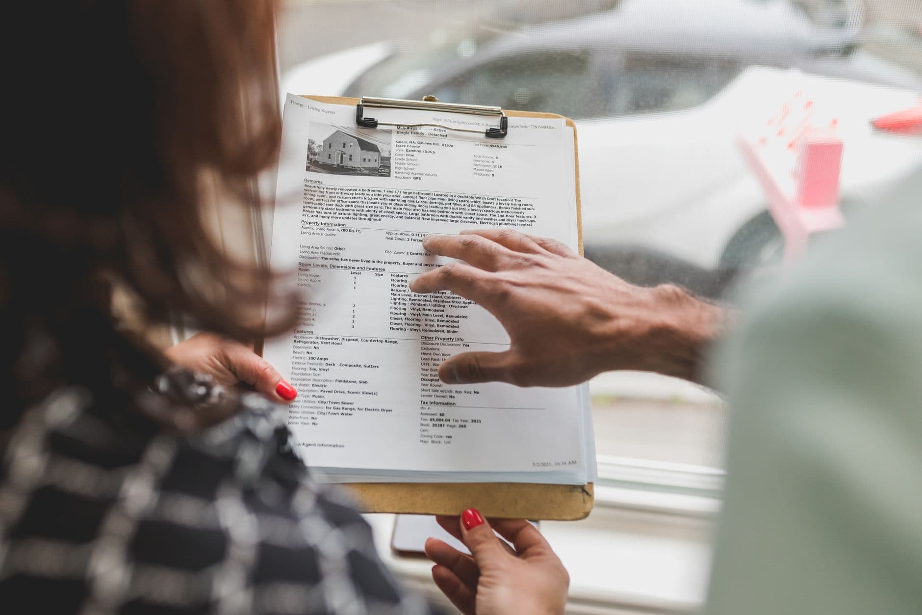 Real estate agent discussing property details with client using a clipboard indoors